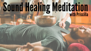 A man lying on the floor with a metal singing bowl on his body with a practitioner striking it. 